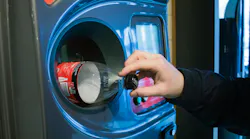 A person returns a plastic bottle to a recycling receptacle.