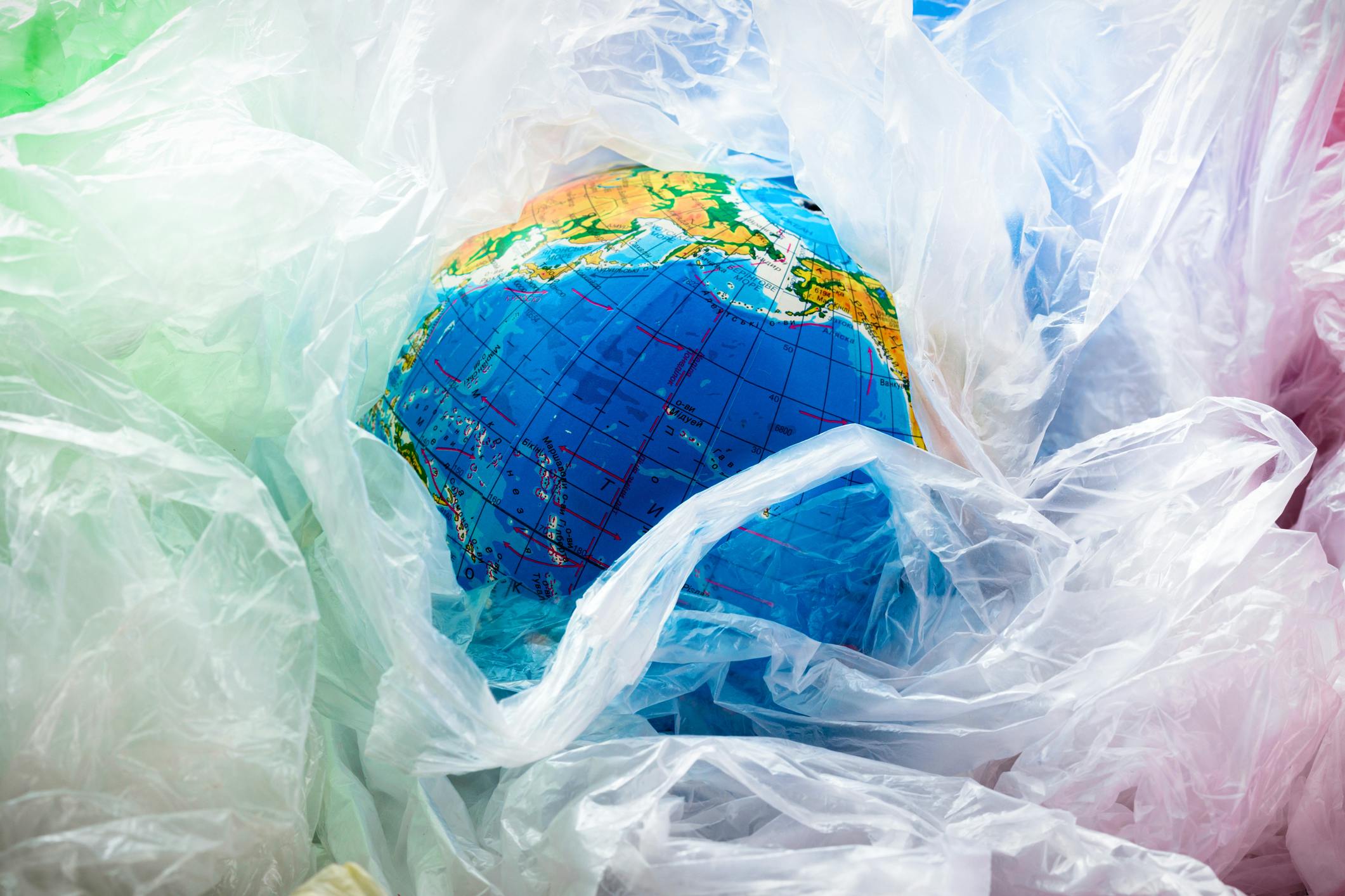 A globe surrounded by plastic bags symbolizes the world's plastic pollution problem.