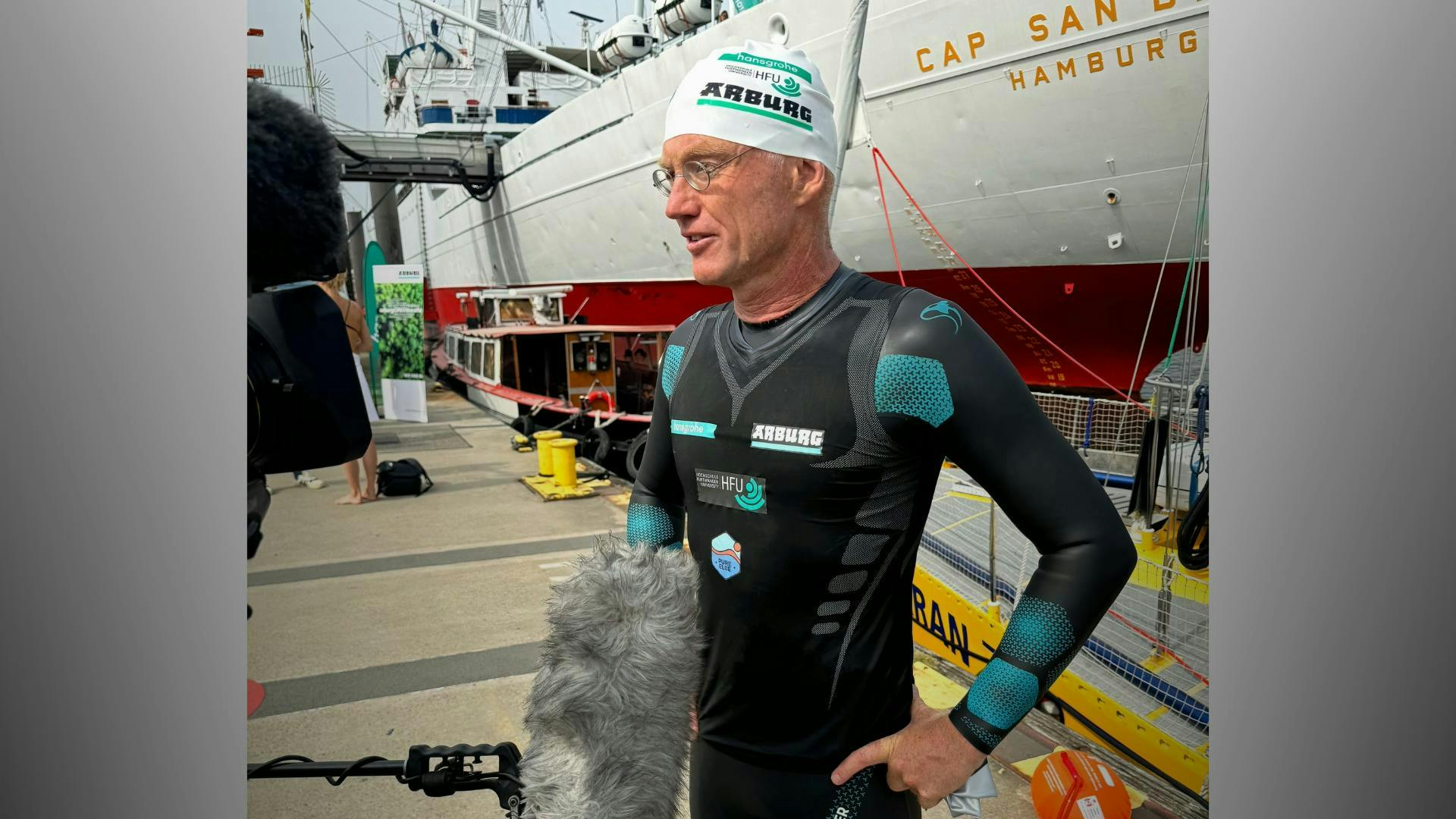 Arburg brand ambassador Andreas Fath, a German chemistry professor, navigates interviews after arriving in Hamburg, Germany, while swimming the Elbe River during one of several events he's organized to highlight the need to protect water resources.