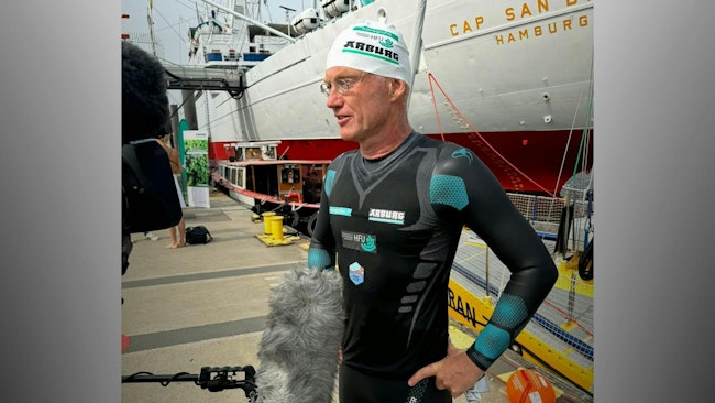 Arburg brand ambassador Andreas Fath, a German chemistry professor, navigates interviews after arriving in Hamburg, Germany, while swimming the Elbe River during one of several events he's organized to highlight the need to protect water resources.