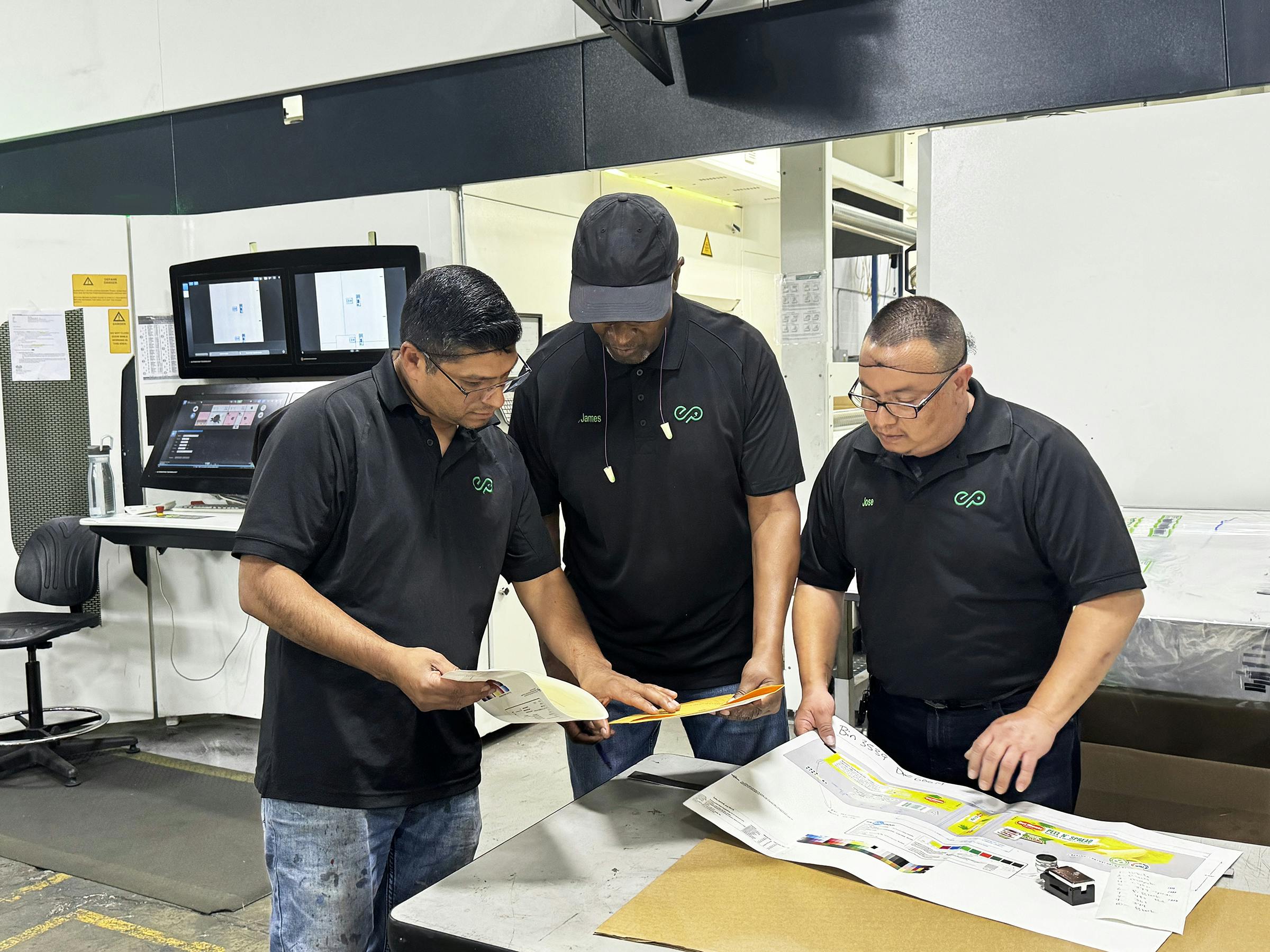 Employees look over materials regarding color matching at Union City, Calif., converter Emerald Packaging.