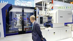 A visitor checks out an injection molding machine at K 2025. A visitor checks out an injection molding machine at K 2025.