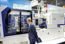 A visitor checks out an injection molding machine at K 2025. A visitor checks out an injection molding machine at K 2025.