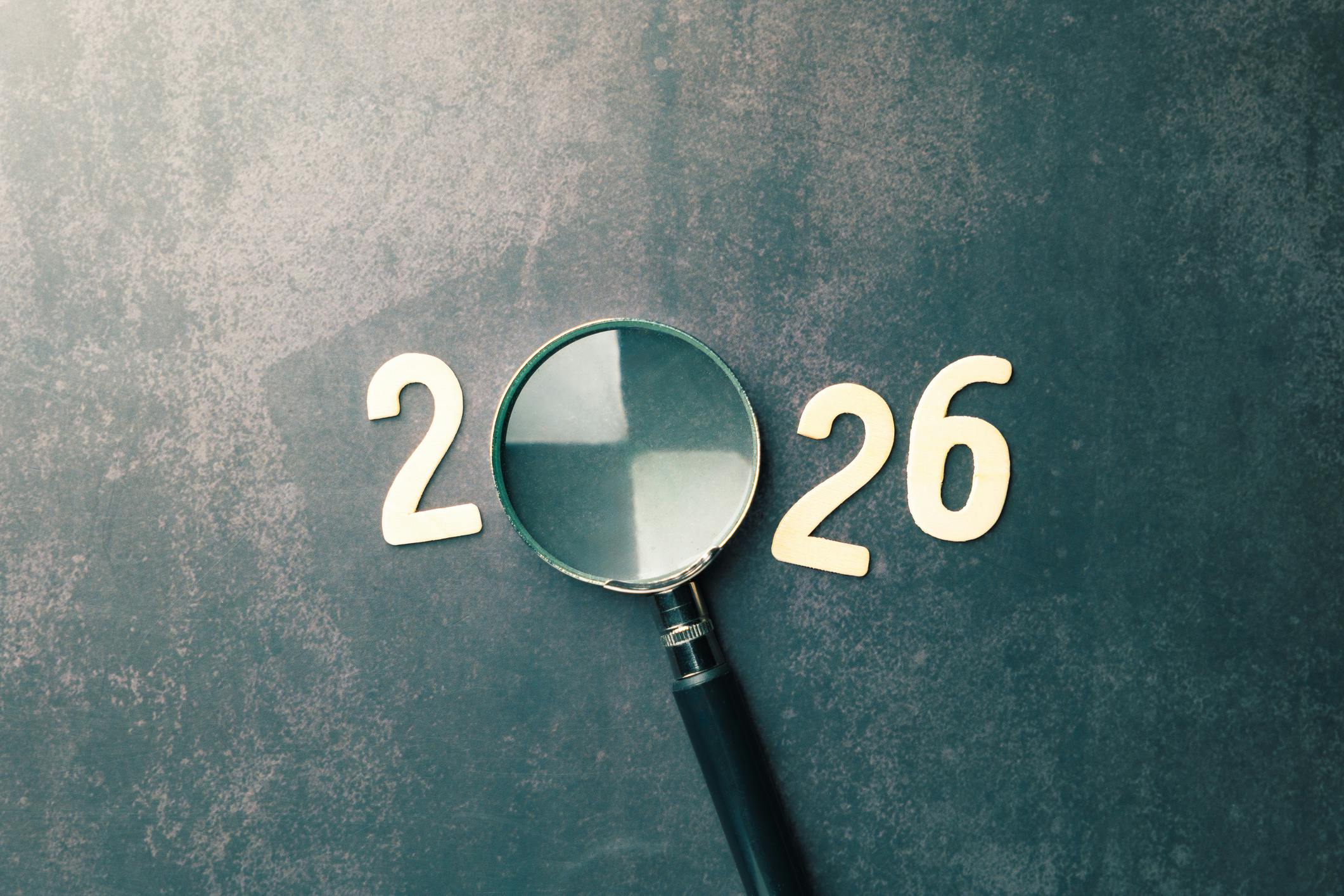 Magnifying glass forms the zero in 2026, looking ahead.