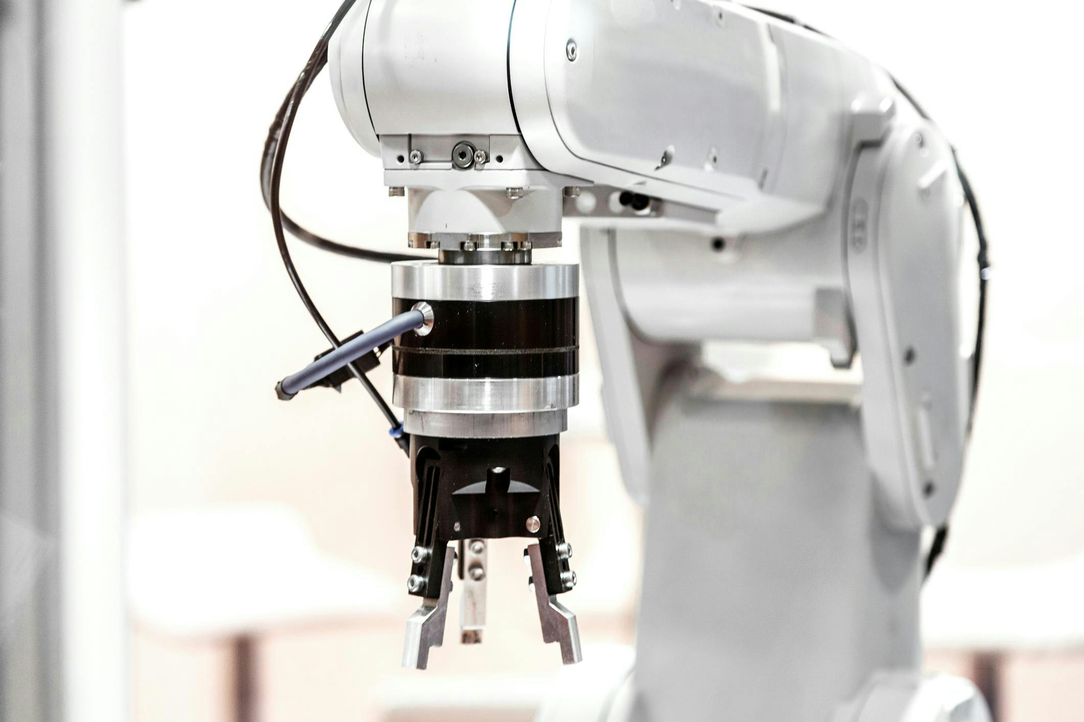 A white industrial robot arm with a gripper end-of-arm tool