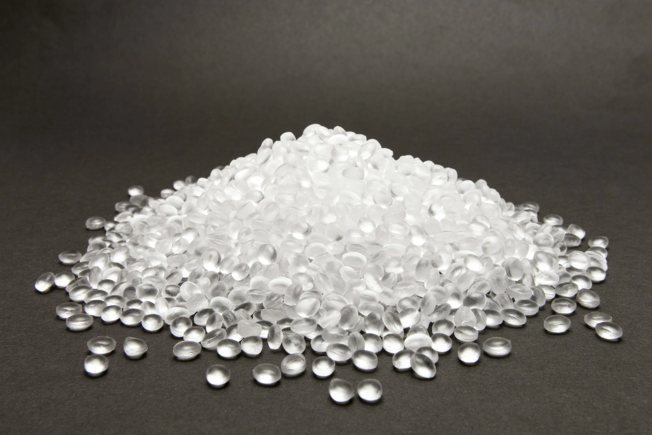 Clear high density polyethylene resin pellets on gray background