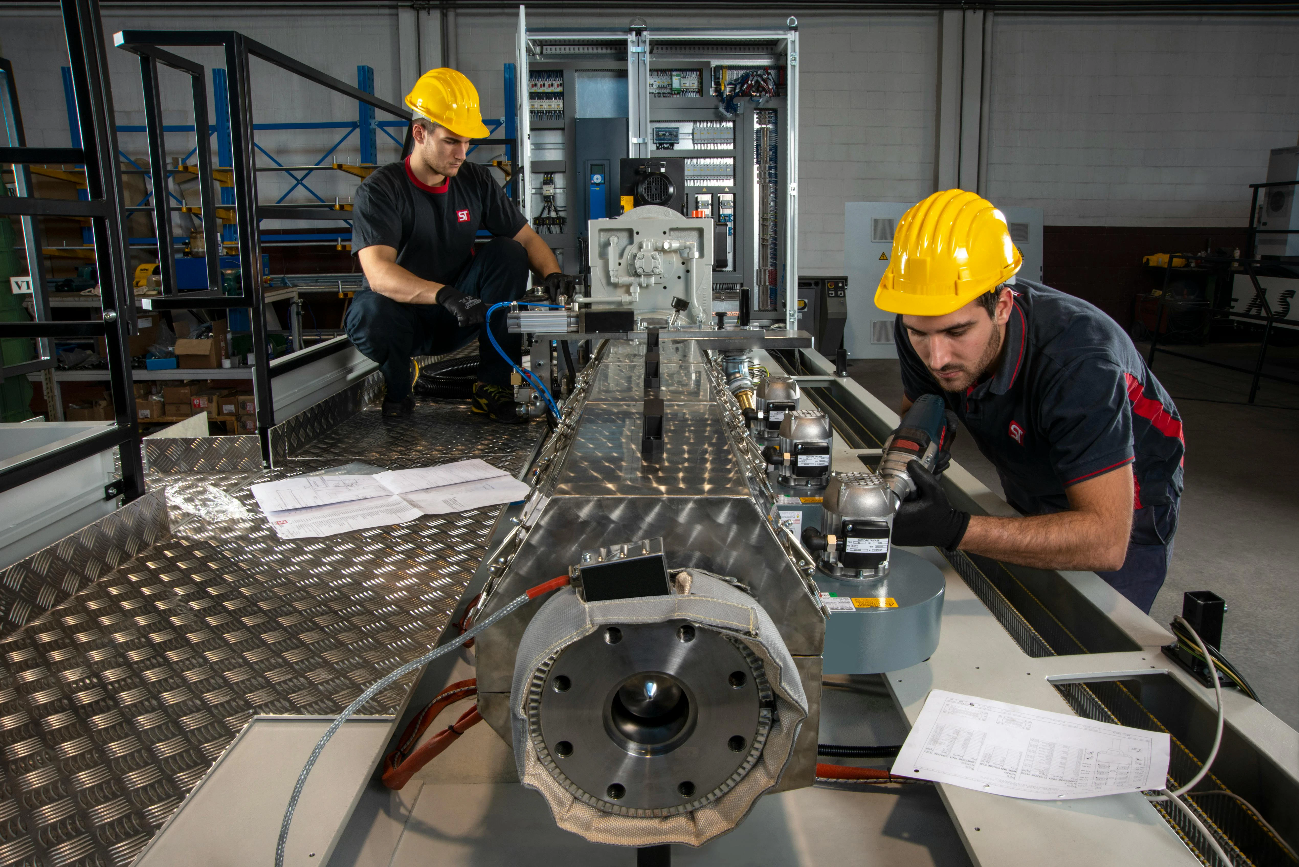 Workers at ST BlowMoulding's facility in Monza, Italy, assemble a blow molding machine.