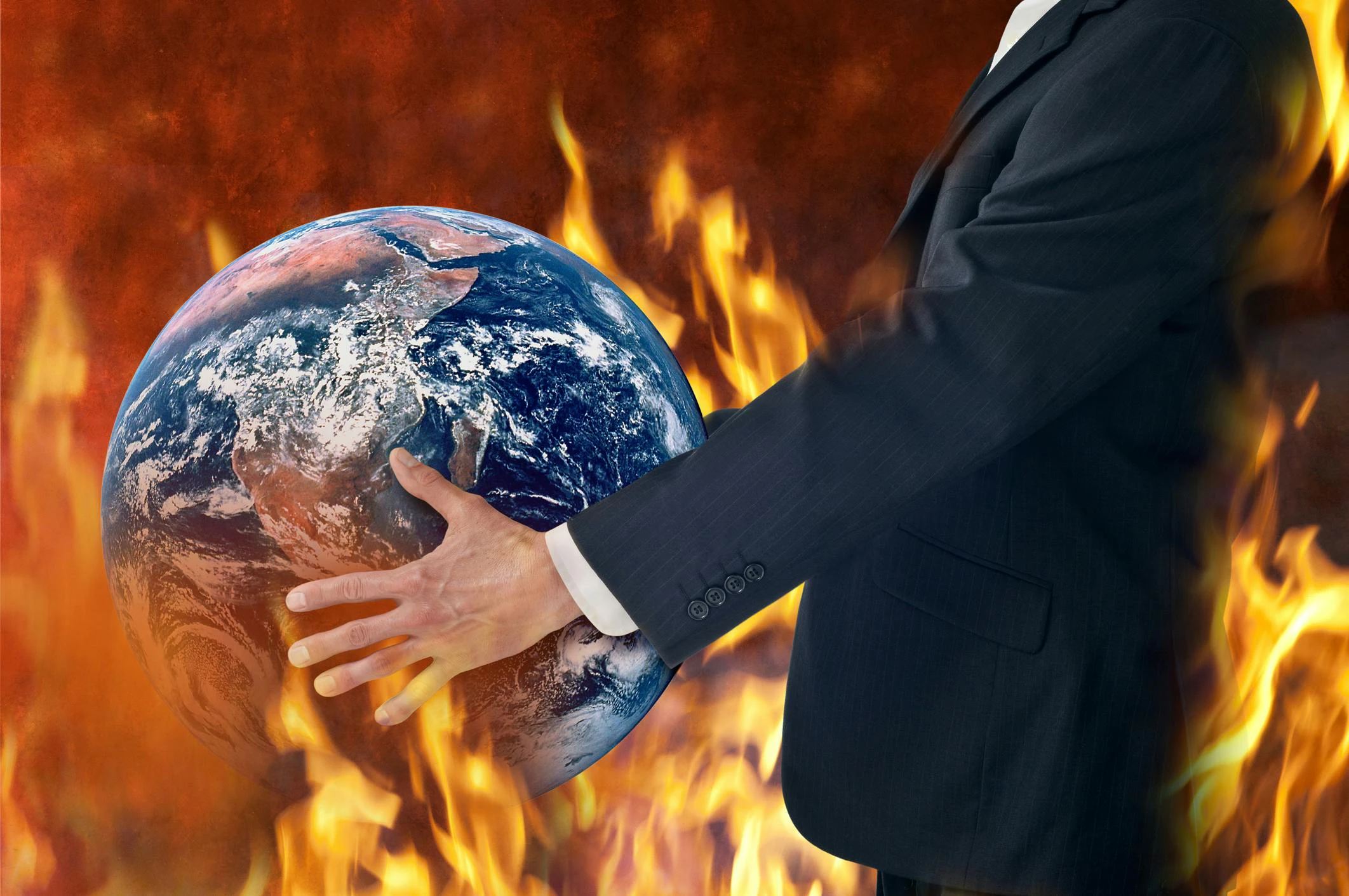 Businessman holds a globe as fires burn around him