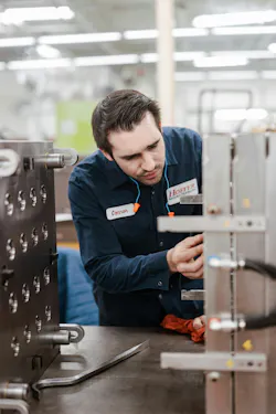 A worker performs maintenance on an injection mold. A worker performs maintenance on an injection mold.