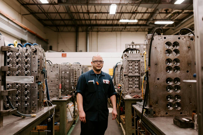 A Hoffer Plastics worker surrounded by injection molds.