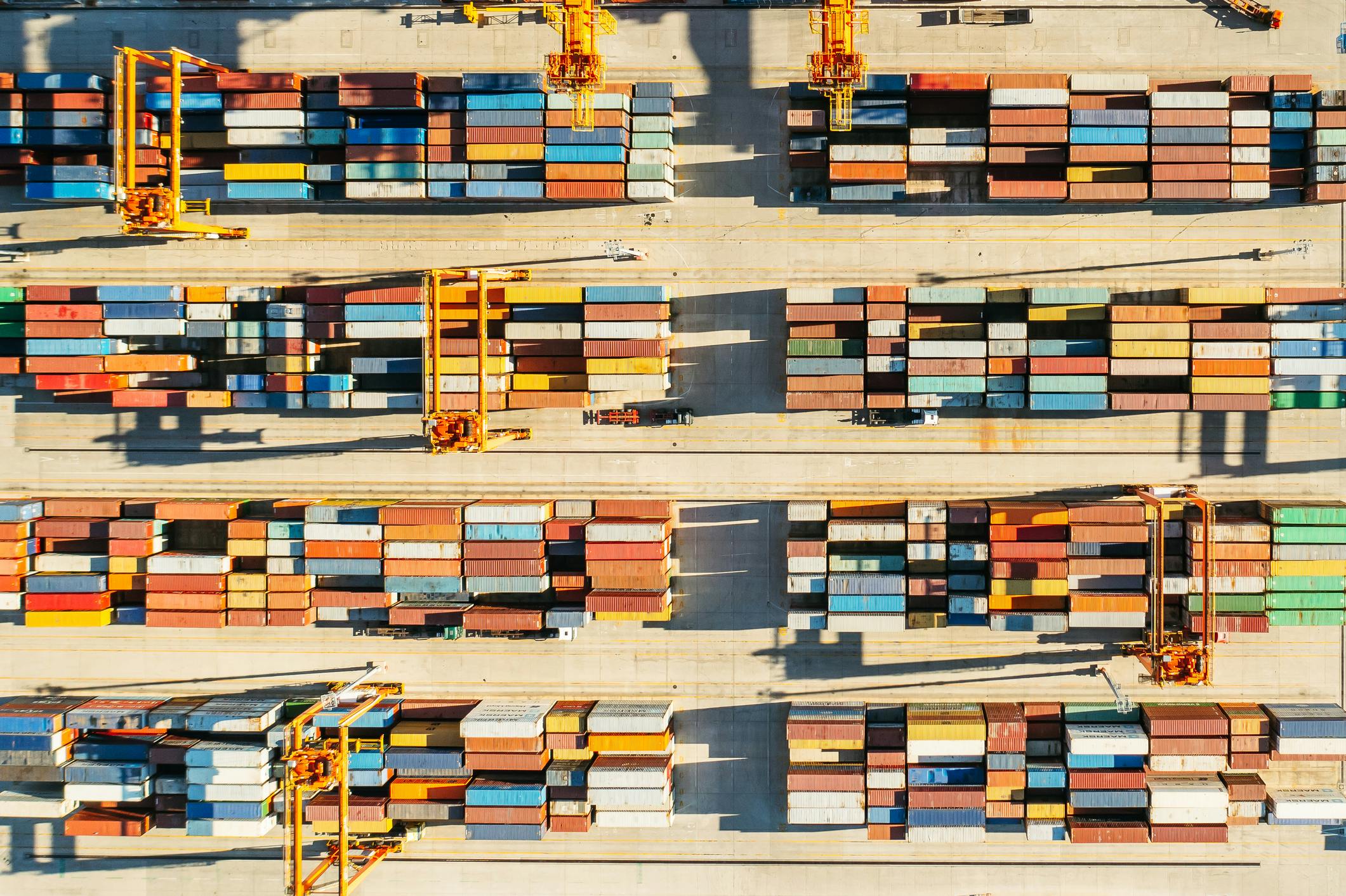 Rows of shipping containers in a port, viewed from above.