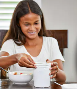 Girl opening a white plastic tub.