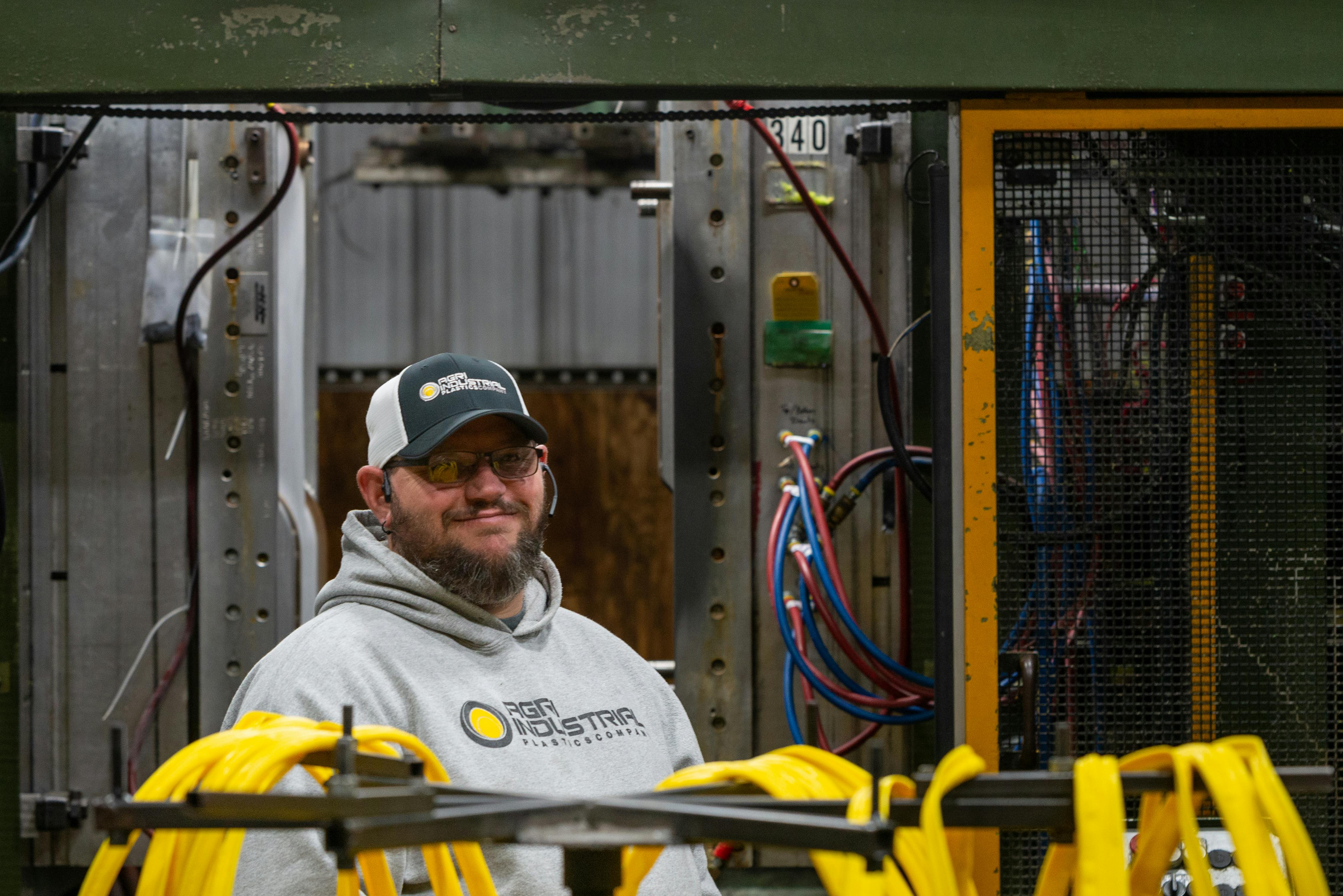 A worker at a blow molding machine at Agri-Industrial Plastics