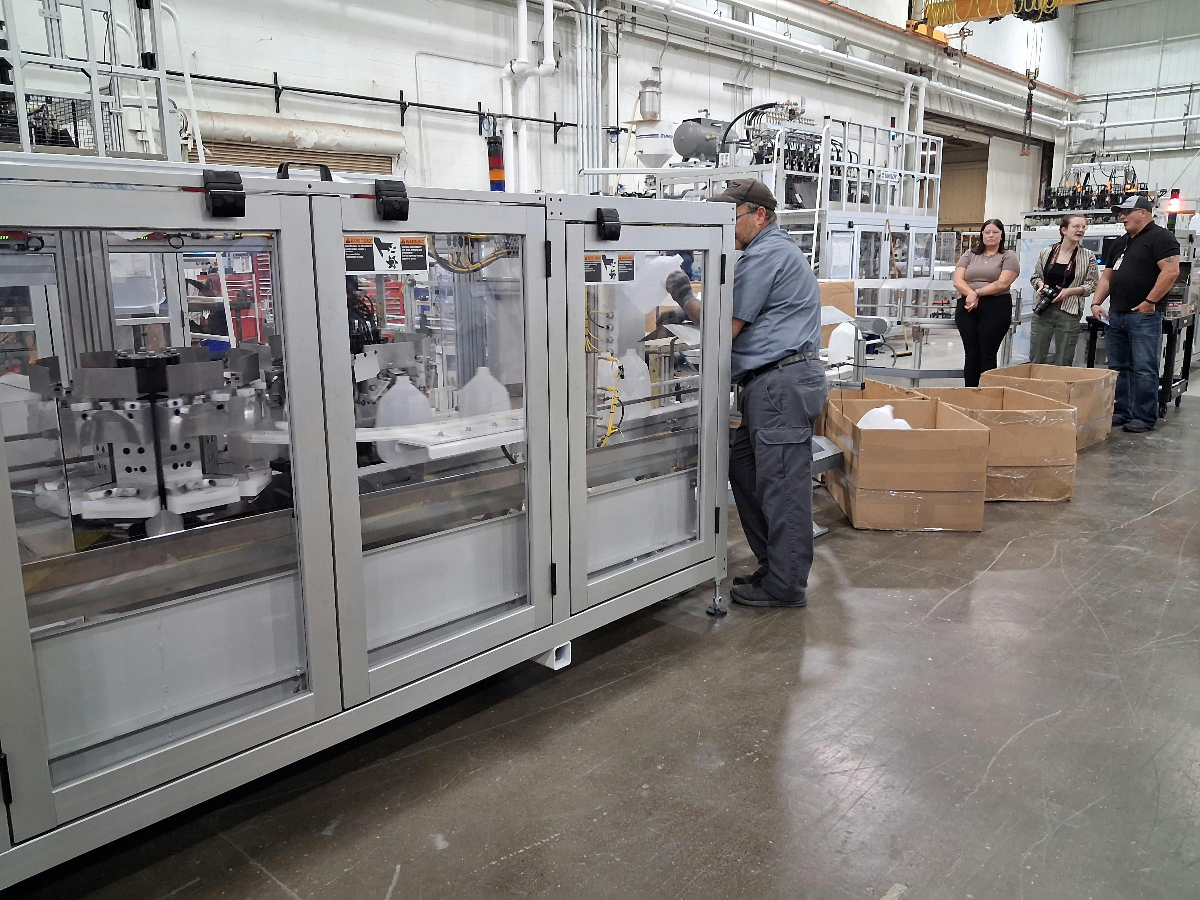 A Uniloy UR 100 12-cavity reciprocating machine produces bottles during the company's open house.