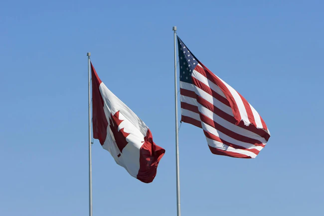 U.S. and Canadian flags against a blue sky