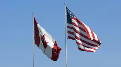 U.S. and Canadian flags against a blue sky