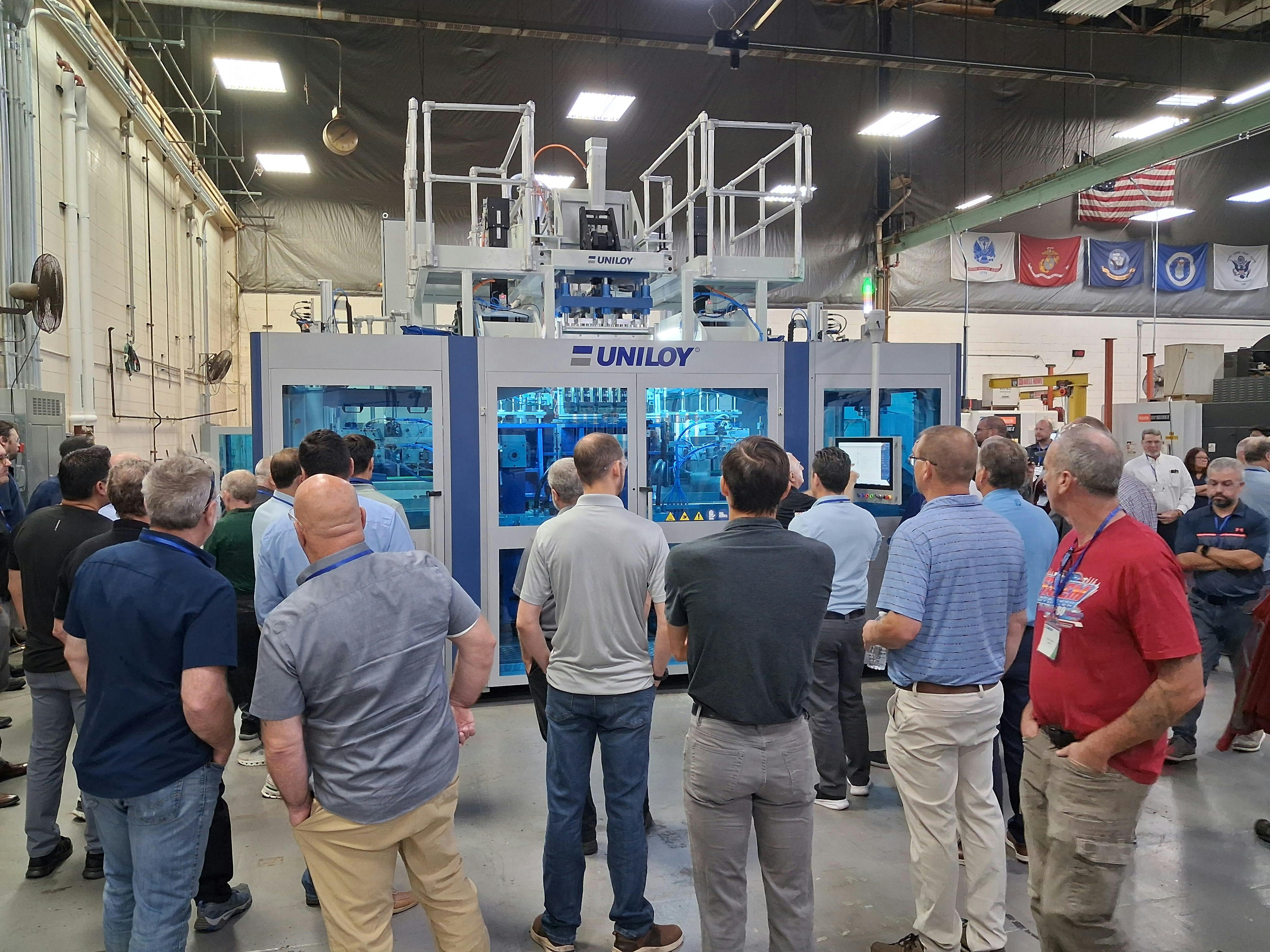 Attendees at Uniloy's open house watch a demonstration of a UCS 30.ED three-layer shuttle blow molding machine.