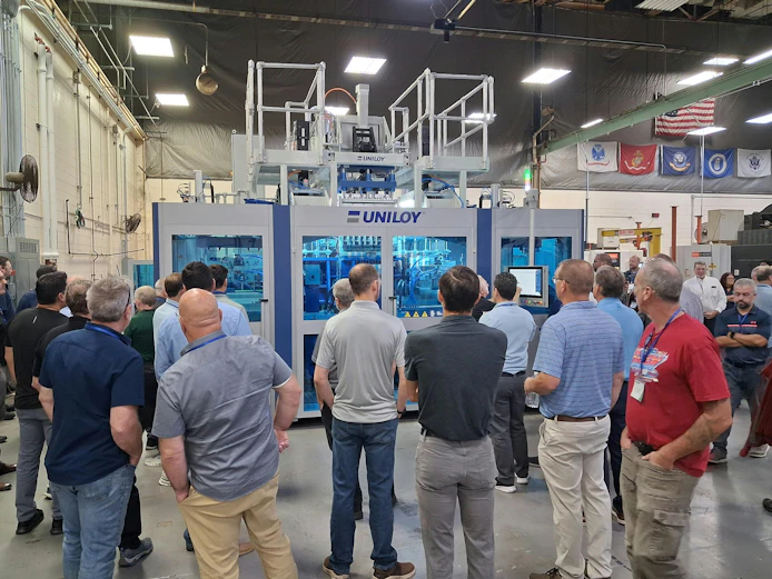 Attendees at Uniloy's open house watch a demonstration of a UCS 30.ED three-layer shuttle blow molding machine.