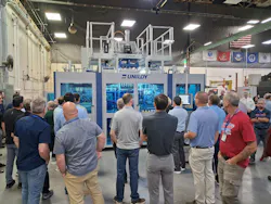 Attendees at Uniloy's open house watch a demonstration of a UCS 30.ED three-layer shuttle blow molding machine.