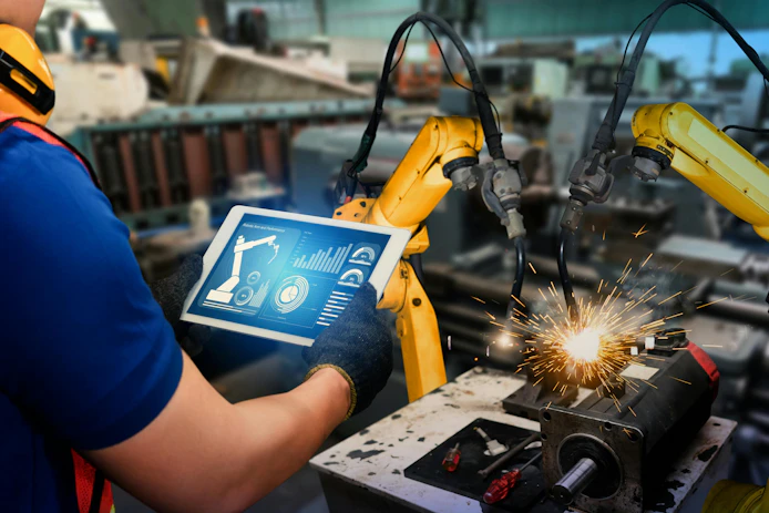 Man with tablet operating an industrial welding robot