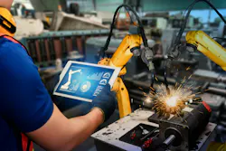Man with tablet operating an industrial welding robot