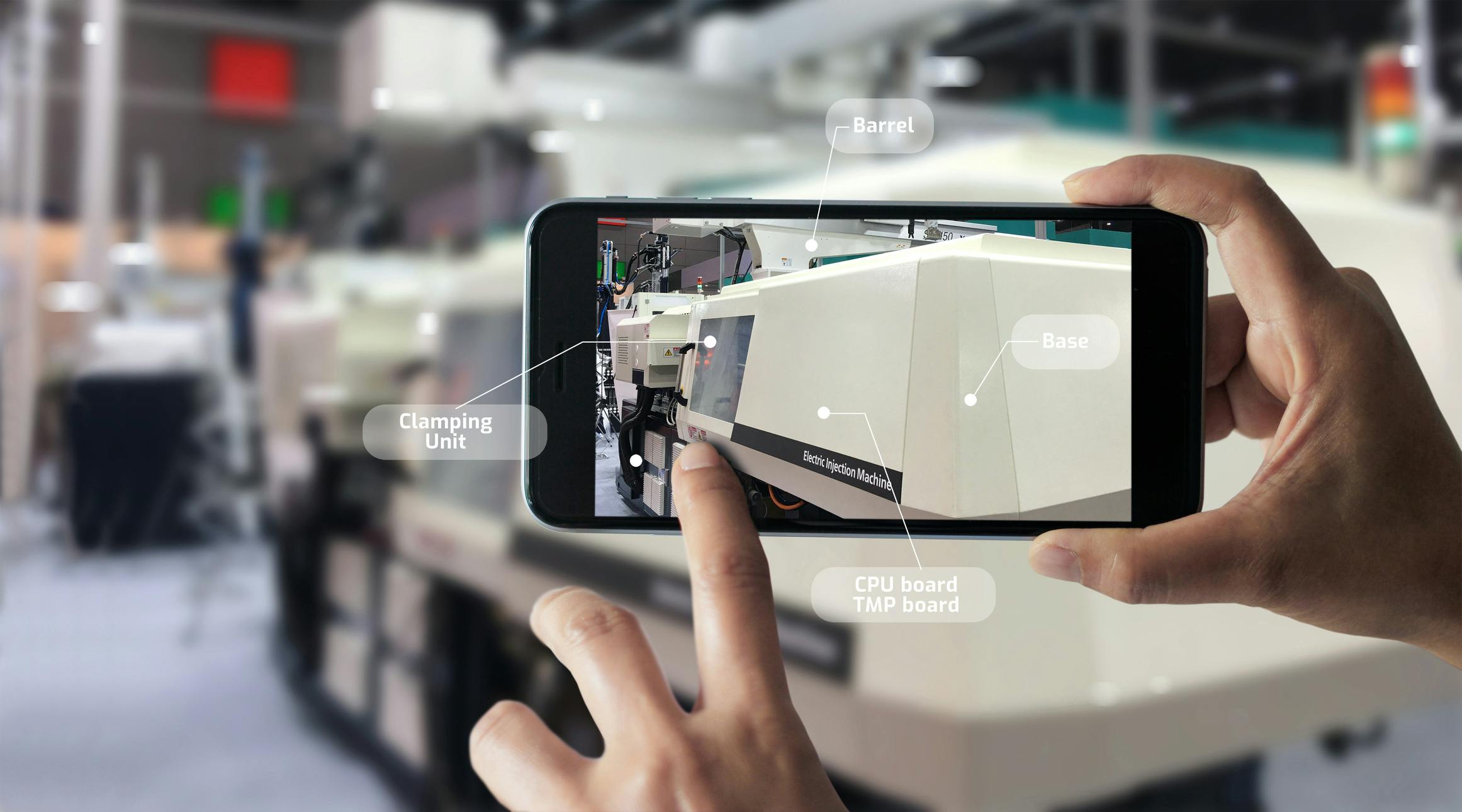 A smartphone shows various parts of an injection molding machine to a user.