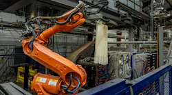 An orange industrial robot on an extrusion blow molding line.