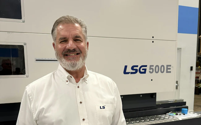 Robert Herman, U.S. Northeast regional sales manager for LS Mtron, standing in front of an injection molding machine..