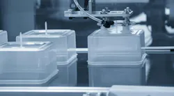 Plastic containers on an injection molding line with an industrial robot.