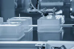 Plastic containers on an injection molding line with an industrial robot.