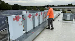 Worker on roof of a plant with solar energy system on a partly cloudy day.