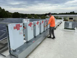 Worker on roof of a plant with solar energy system on a partly cloudy day.