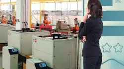 Photo illustration shows a female executive pensively looking at a plastics production floor.