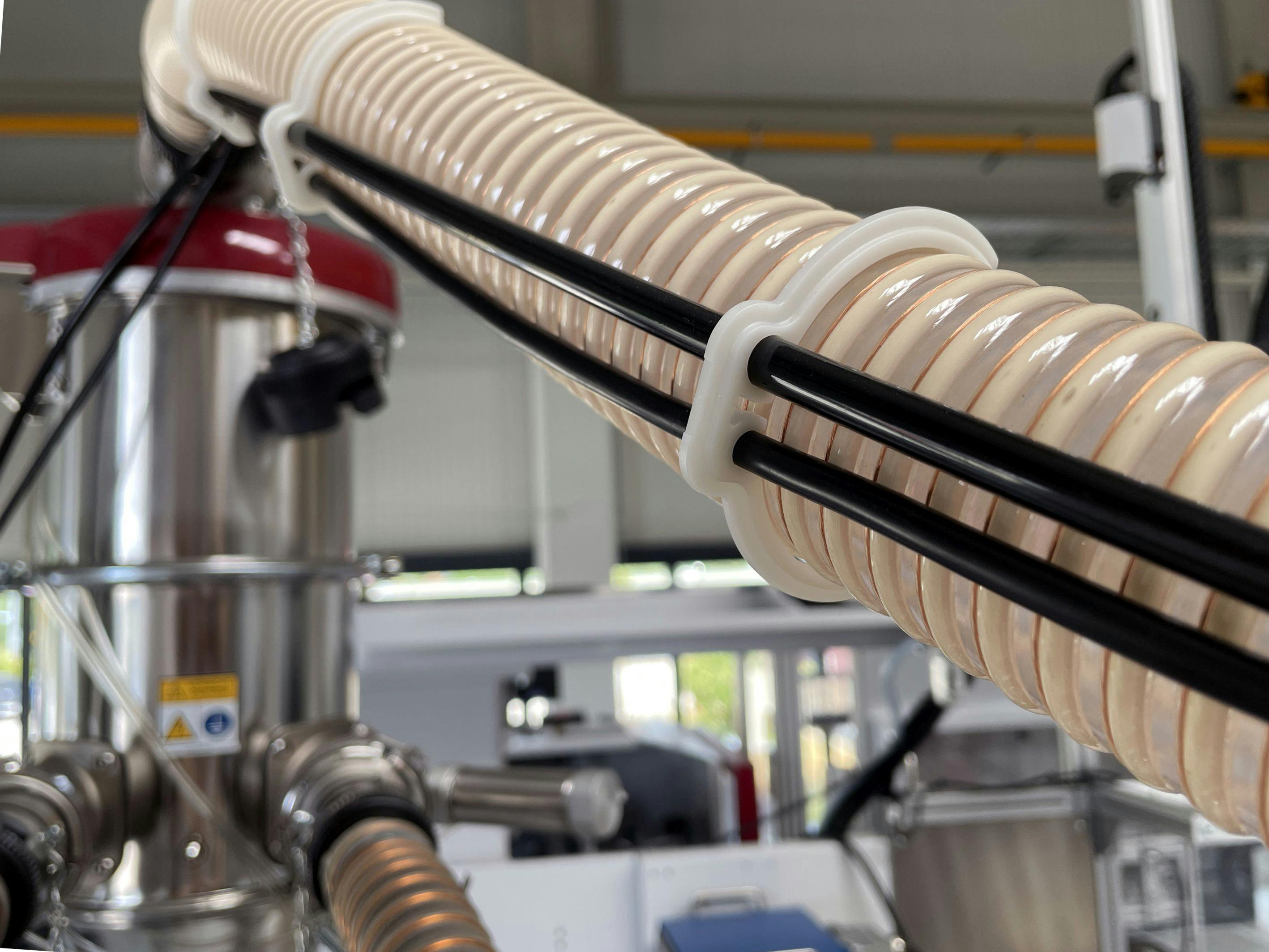 These EcoFritz clamps, produced in a circular Wittmann molding cell, replace single-use zip ties in connecting cables to corrugated hoses.