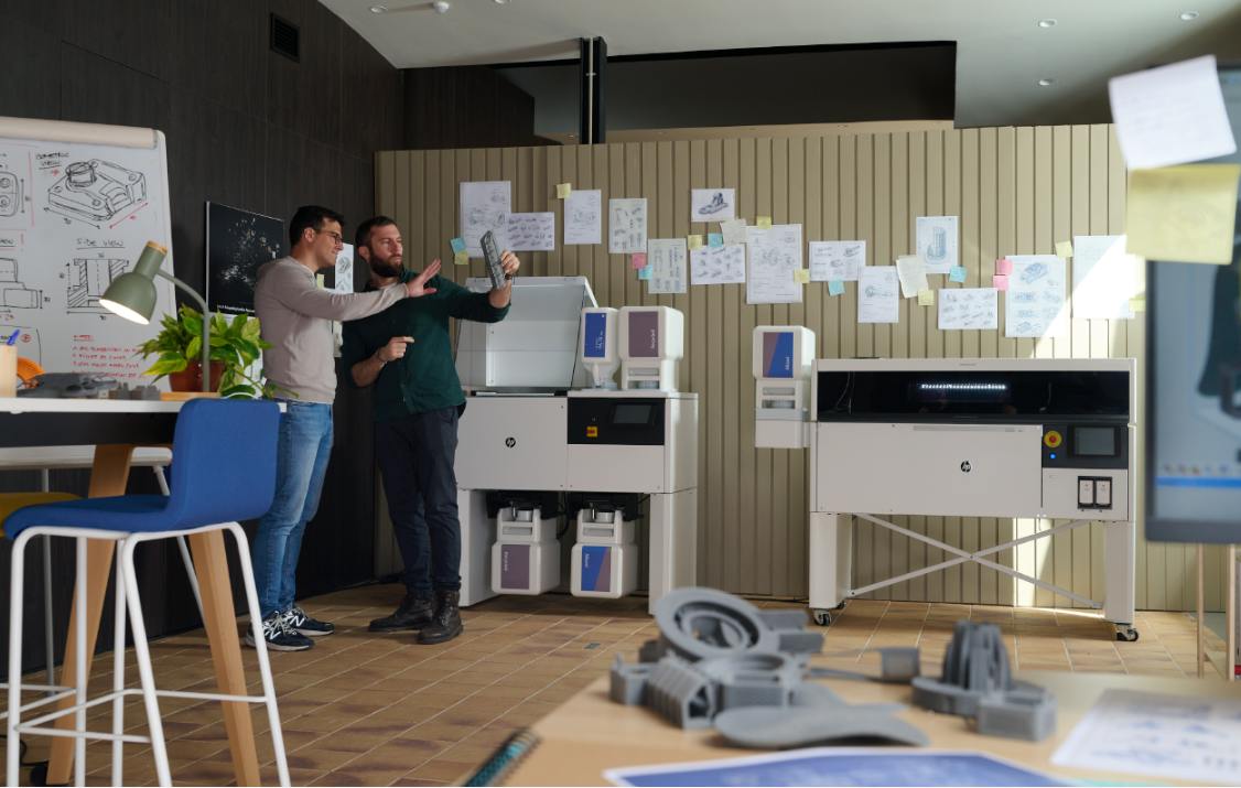 Two men examine a part printed by the HP MJF 1200