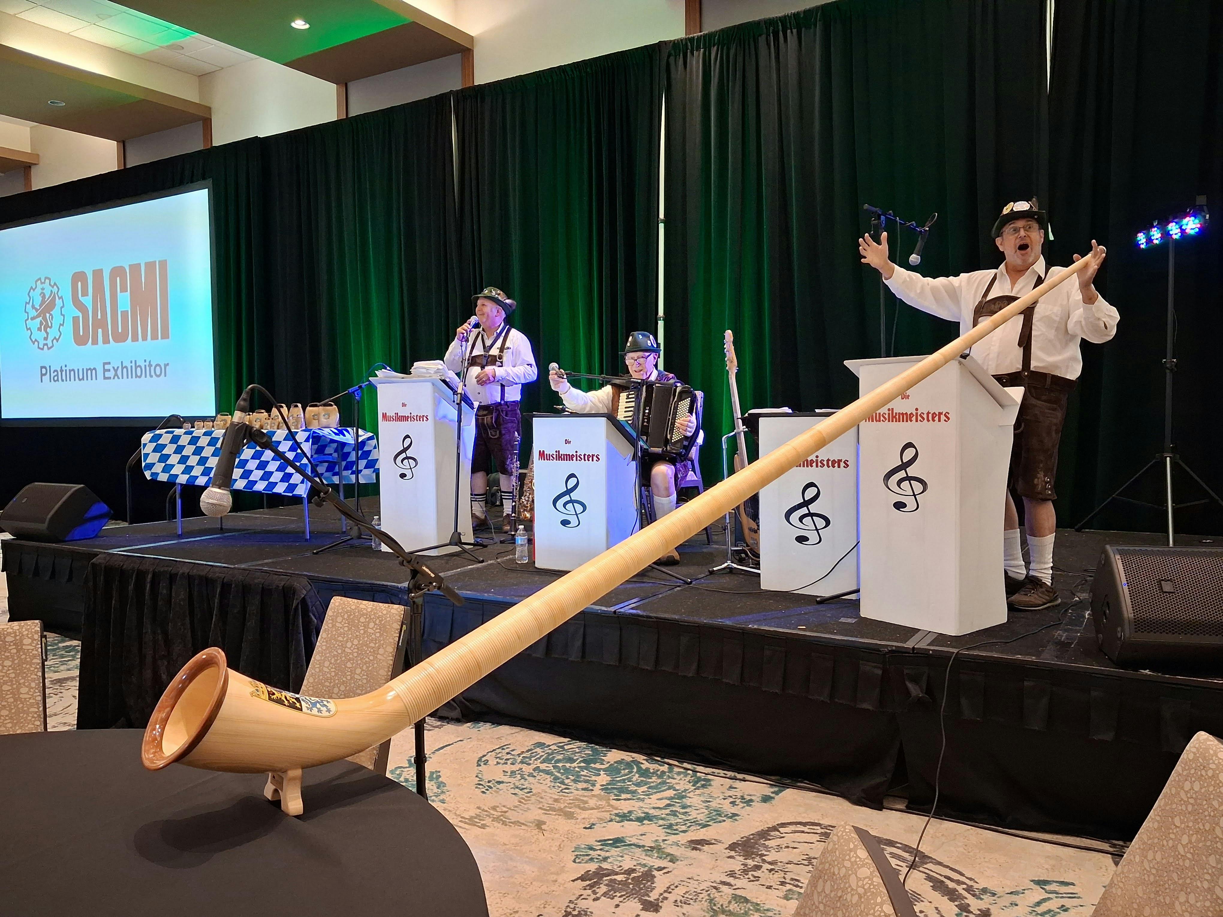 The Musikmeisters play on a stage, including a man with a long alphorn