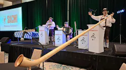 The Musikmeisters play on a stage, including a man with a long alphorn