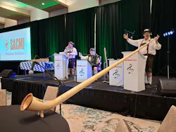 The Musikmeisters play on a stage, including a man with a long alphorn