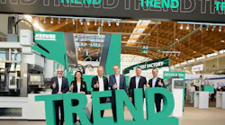 Arburg's management team poses behind a green sign for the 'Trend' machine