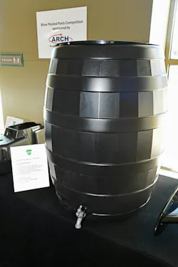 A black plastic 50-gallon rain barrel on a display table.