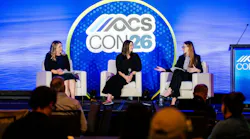 Three women speak on a stage in front of an OCS CON logo.