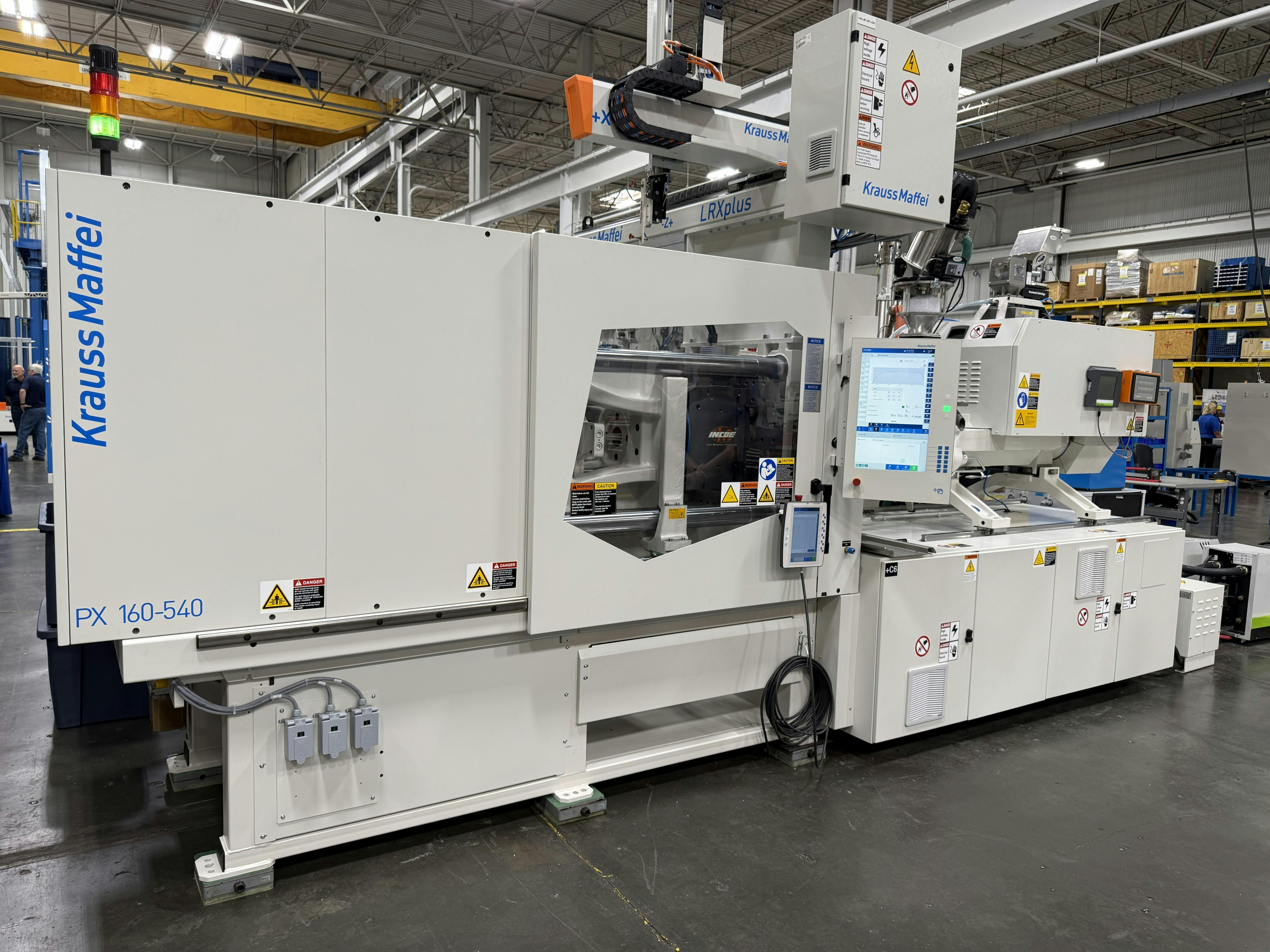 A white KraussMaffei injection molding machine on the company's floor.