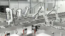 Five white industrial robots work on server components.