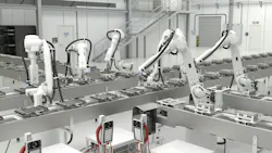 Five white industrial robots work on server components.