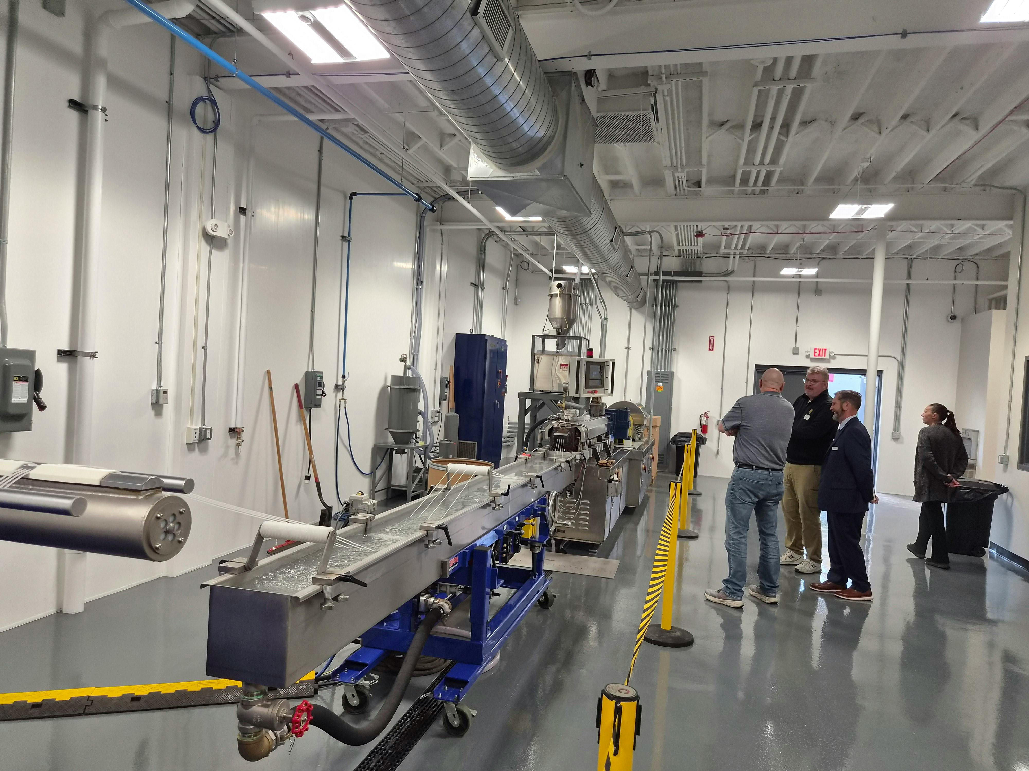 People watch a plastics strand pelletizer in action.