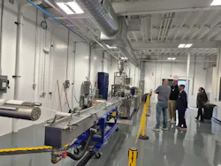 People watch a plastics strand pelletizer in action.