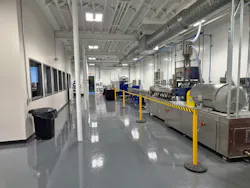 A view of an industrial facility with a conference room on the left and a plastics pelletizer on the right.